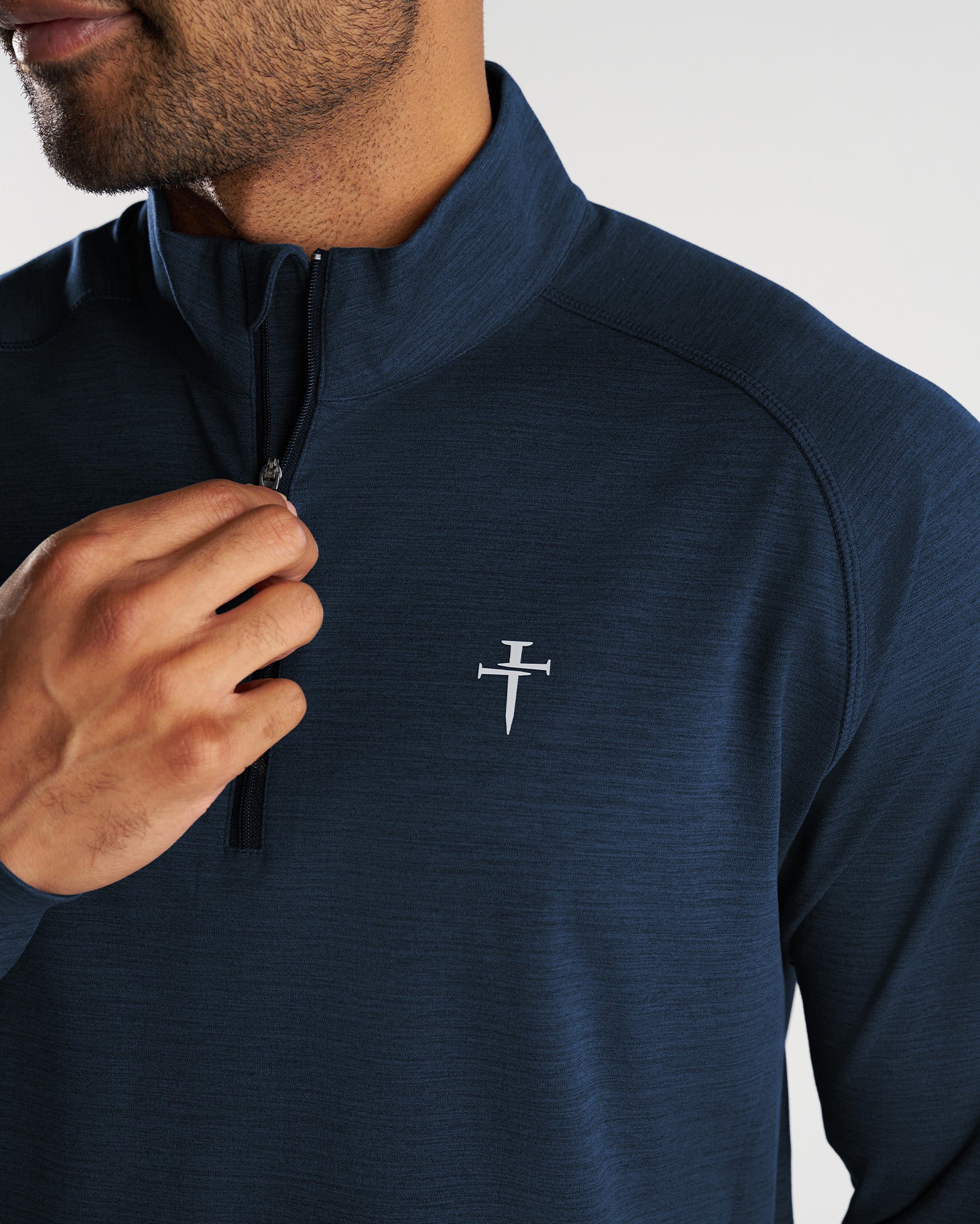 Close-up of Core Quarter Zip in Midnight Navy showing chest logo detail and quarter zip collar on male model.