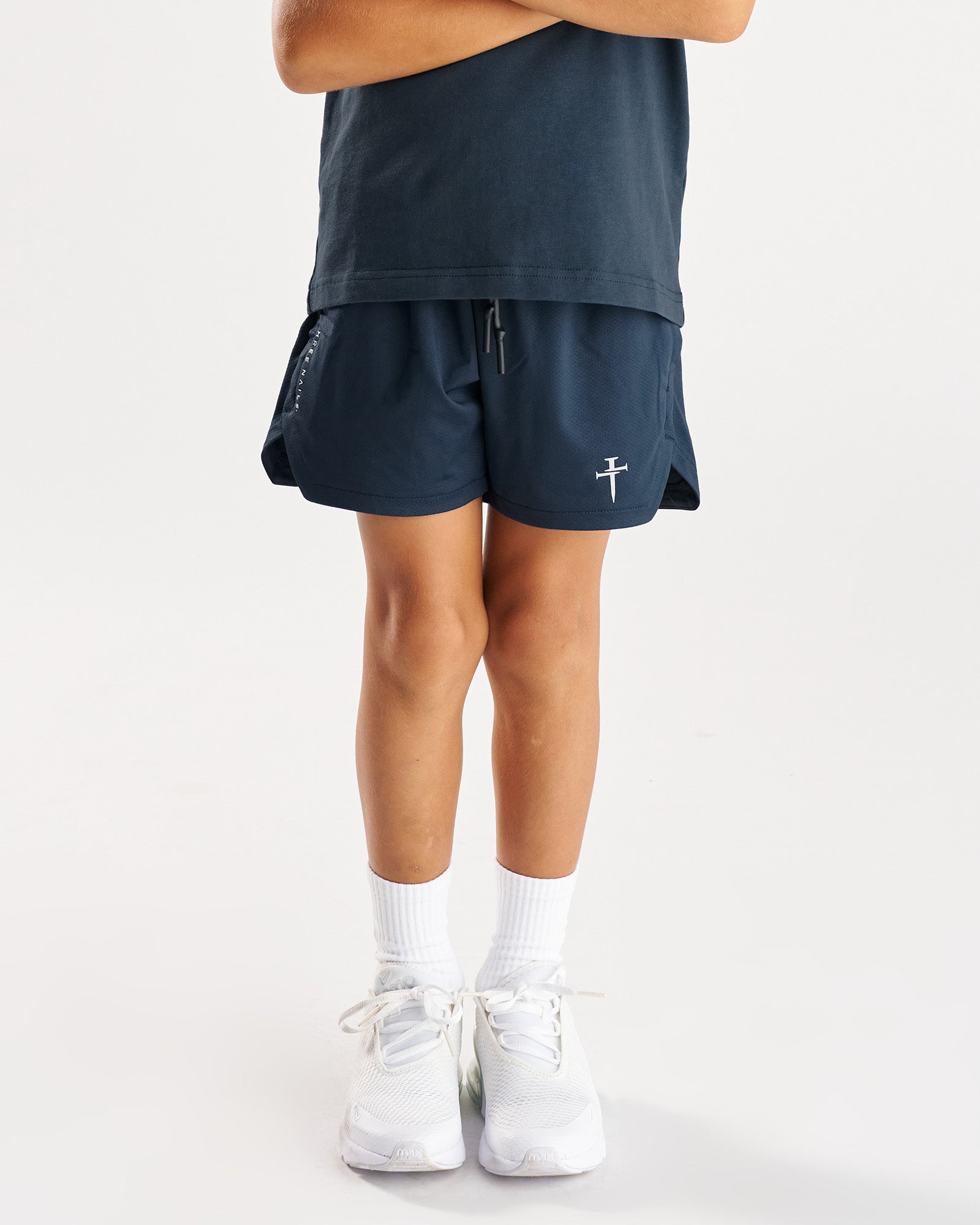 Youth Pro-Tech 2.0 Linerless Short in Midnight Navy, front view on child model with white sneakers and socks.