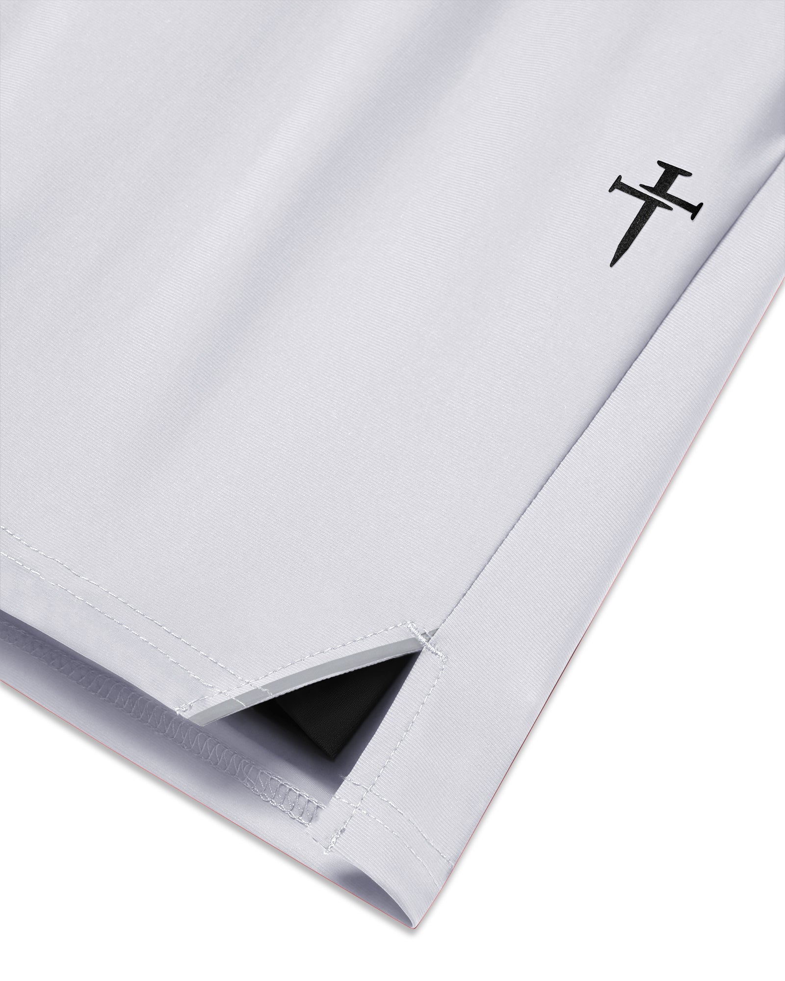 Close-up of Vapor-Lite Liner Short Cross in Stone showing side hem vent and embroidered cross logo detail.