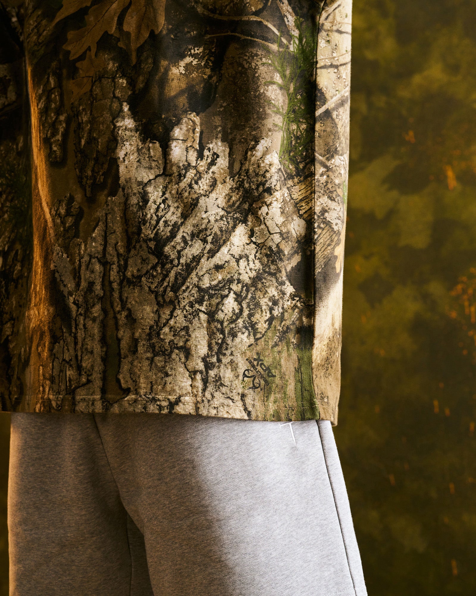 Close-up side detail of the Heavyweight Cotton Oversized Tee FHG in Realtree Camo showing hem and sleeve edge.