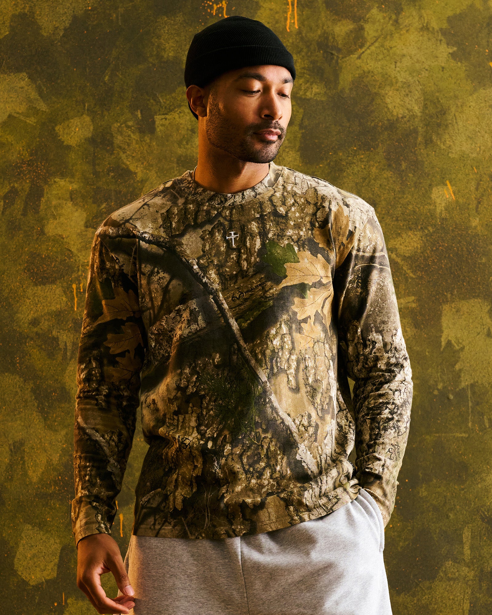 Man wearing Heavyweight Cotton Oversized Long Sleeve FHG in Realtree Camo, front view, black beanie, relaxed pose.