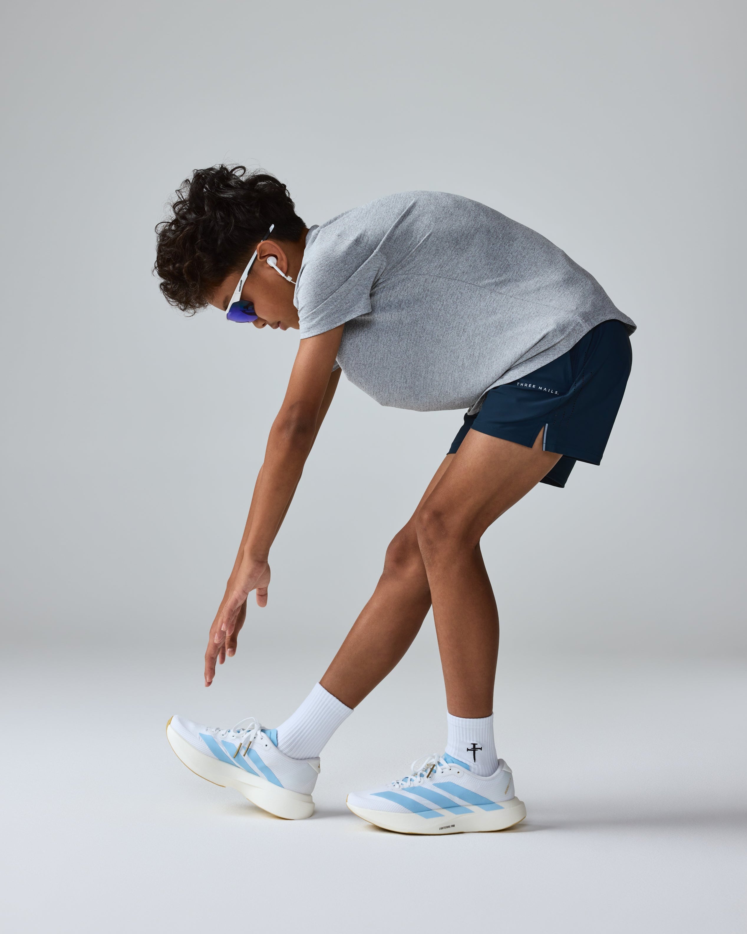 Youth Vapor-Lite Hybrid Short in Midnight Navy shown on a model bending forward, side angle view.