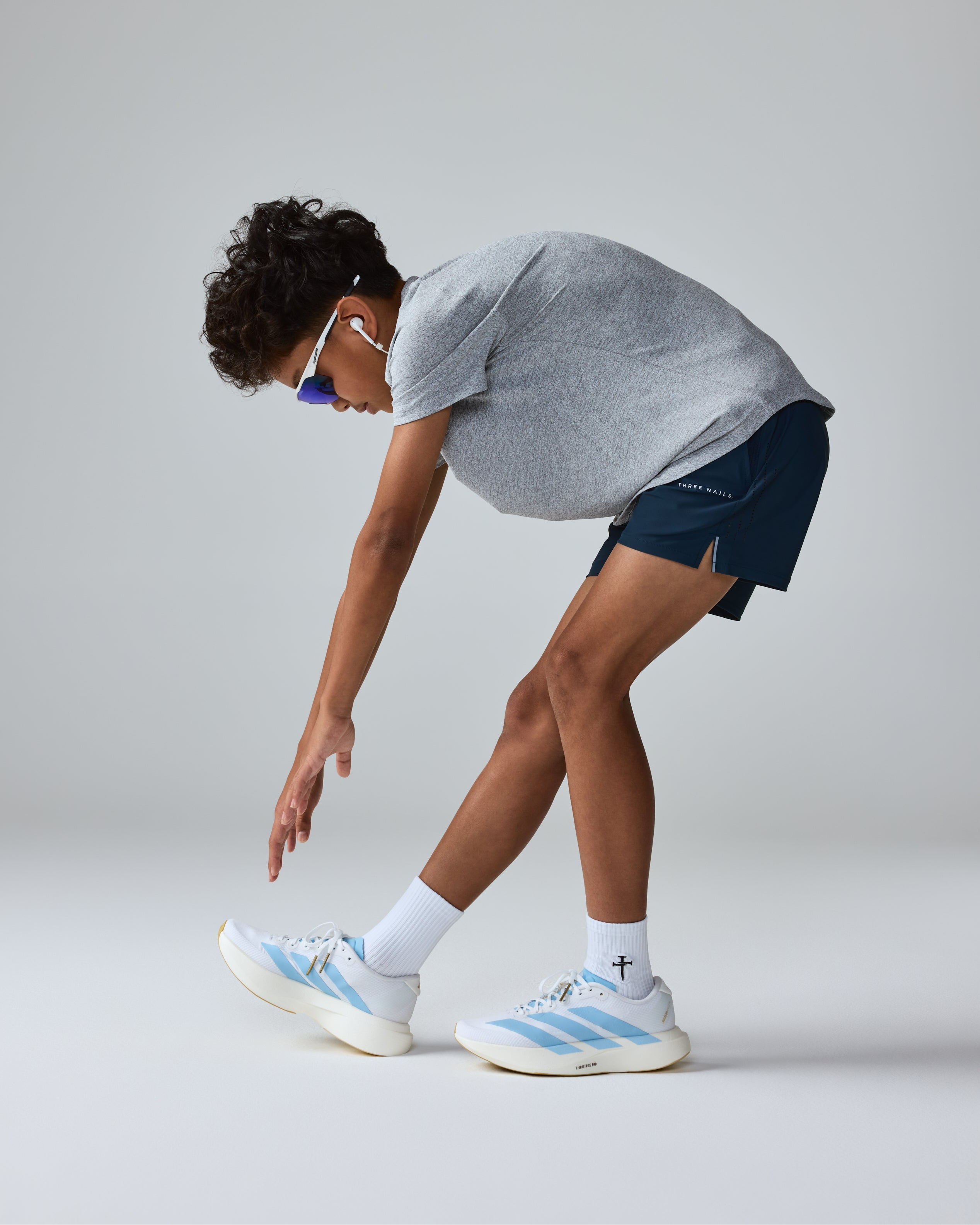 Youth Aion-Lite Tee Cross in Sky Blue Marl on a model bending forward, side angle view.