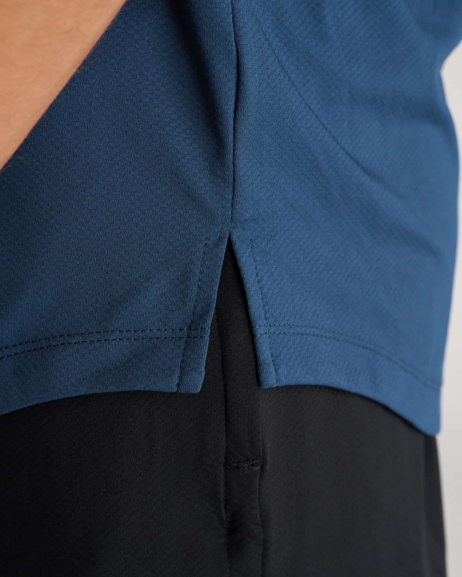 Close-up detail of the Pro-Tech Tee Cross in Midnight Navy showing the side hem split and stitching.