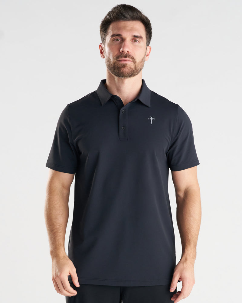 Man wearing black Vented Tech Polo, front view, with small cross logo on chest.