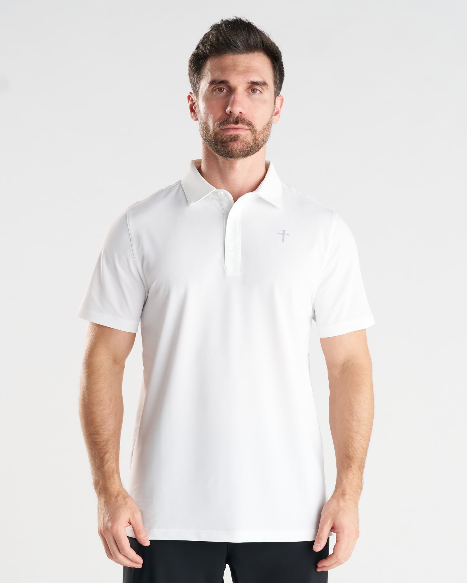 Man wearing white Vented Tech Polo, front view, featuring subtle cross logo and button placket.
