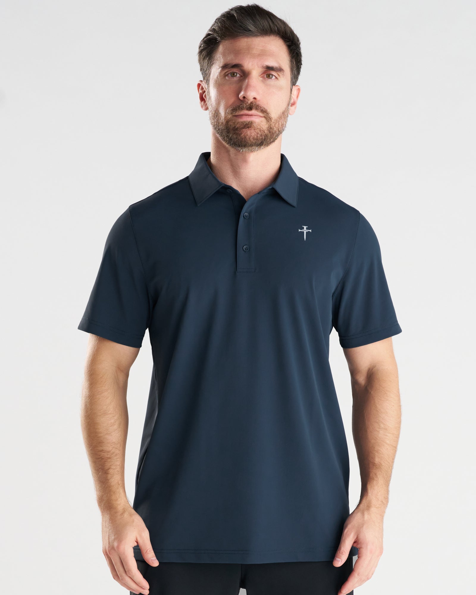 Man wearing a navy Vented Tech Polo, front view, featuring a small cross logo on the chest.