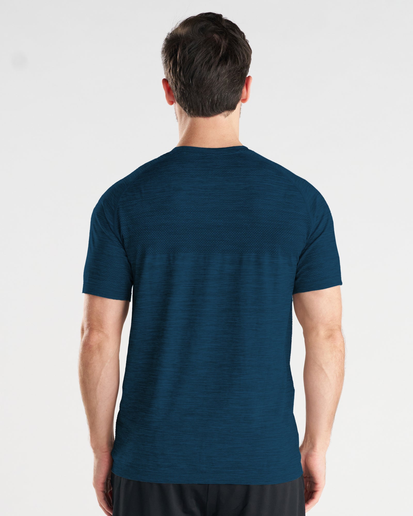 Back view of model wearing the Seamless Tee in Midnight Navy, showing textured mesh panel across upper back.