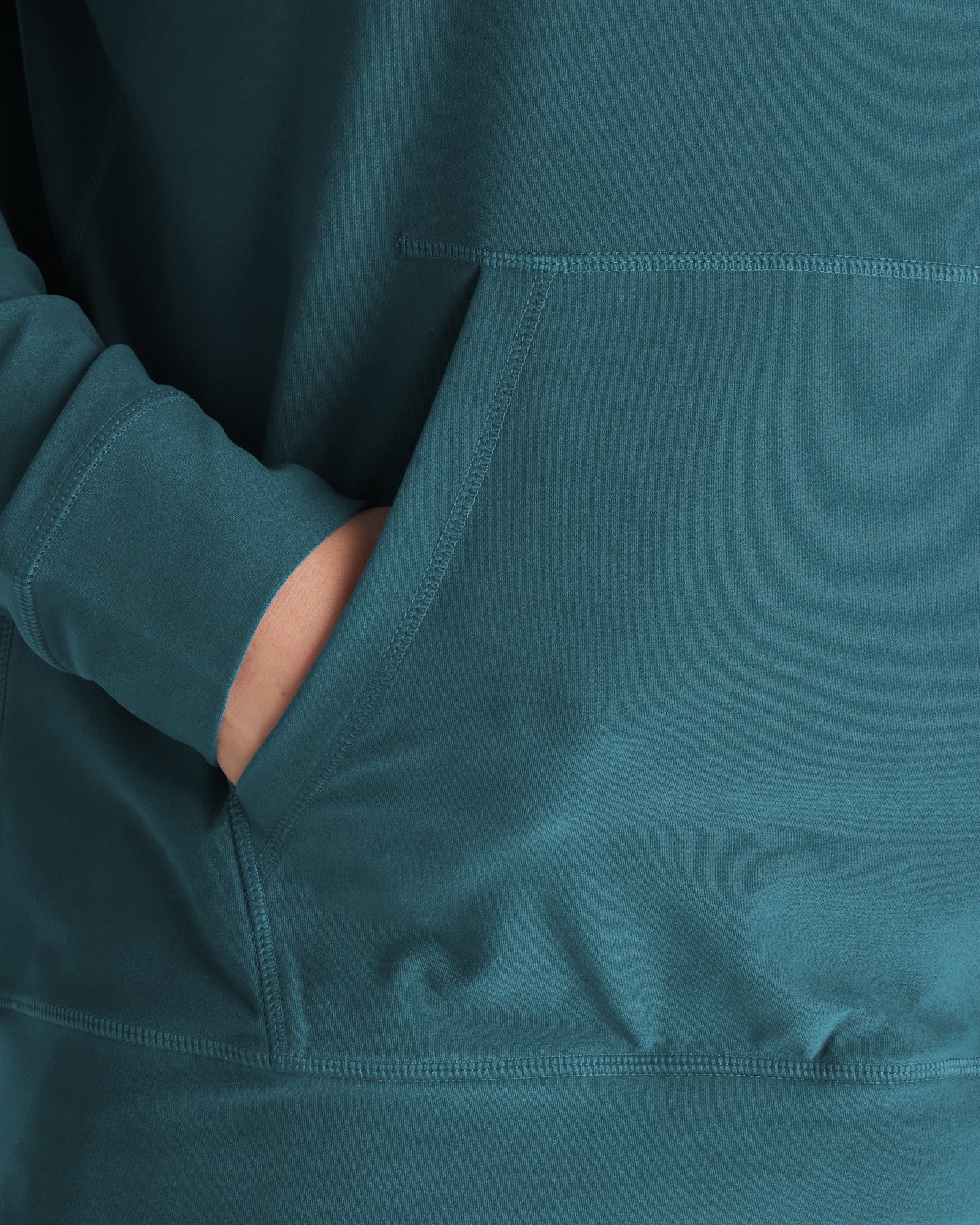 Haven Performance Hoodie in teal, close-up detail of front kangaroo pocket with hand inserted.