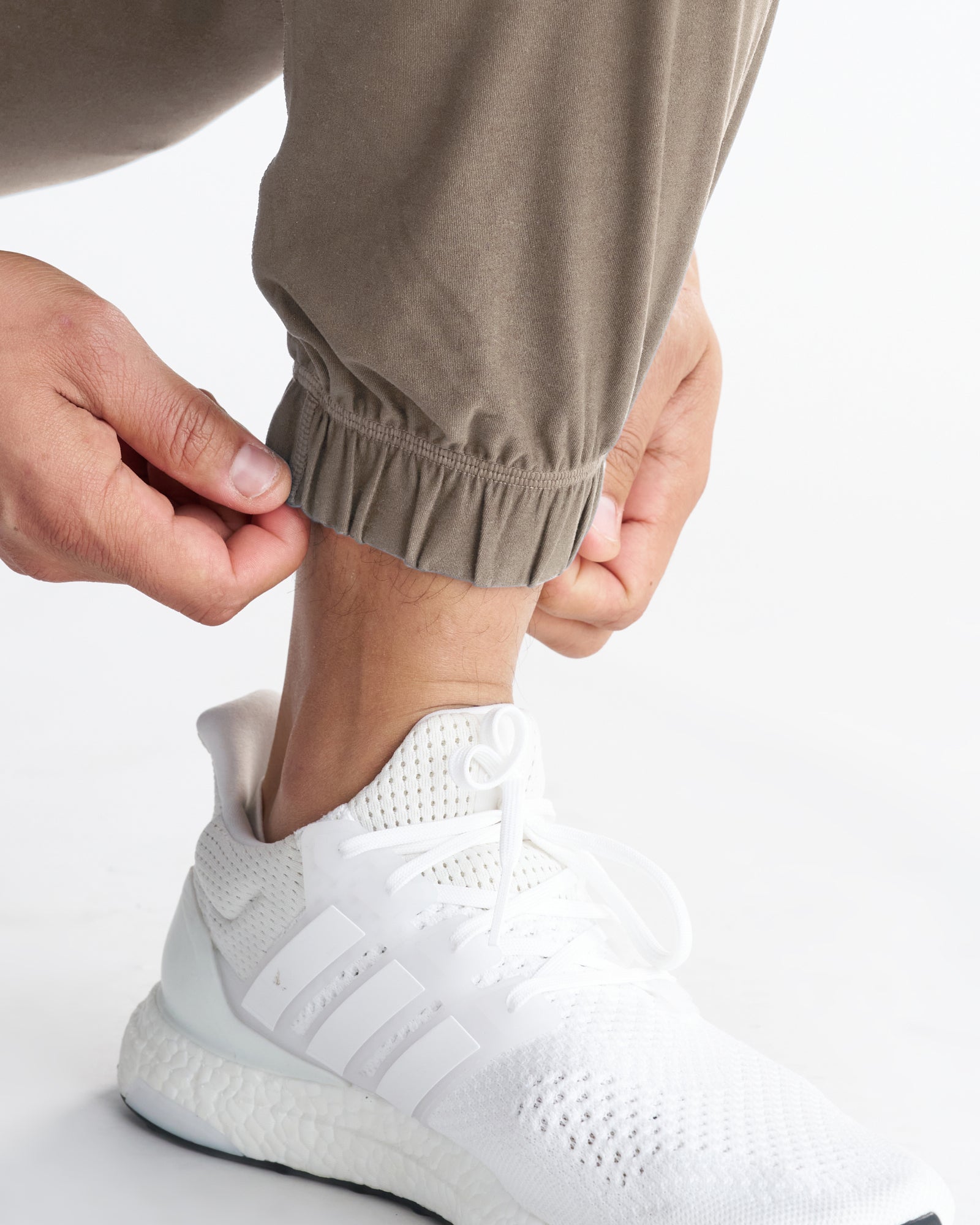 Close-up of Haven Performance Jogger in Sand showing elastic ribbed ankle cuff with white Adidas sneaker.
