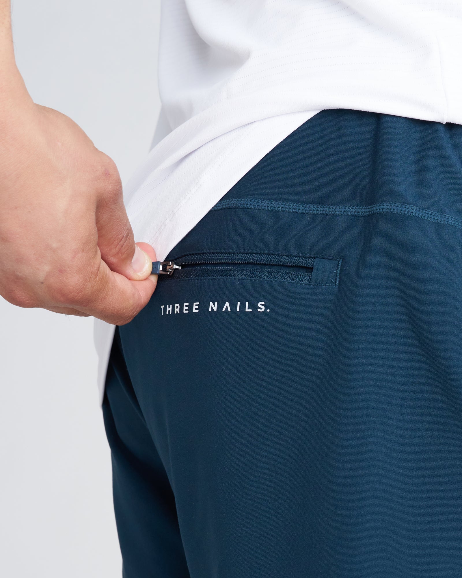 Close-up of the Haven Performance Jogger in Midnight Navy showing a zippered back pocket with Three Nails branding.