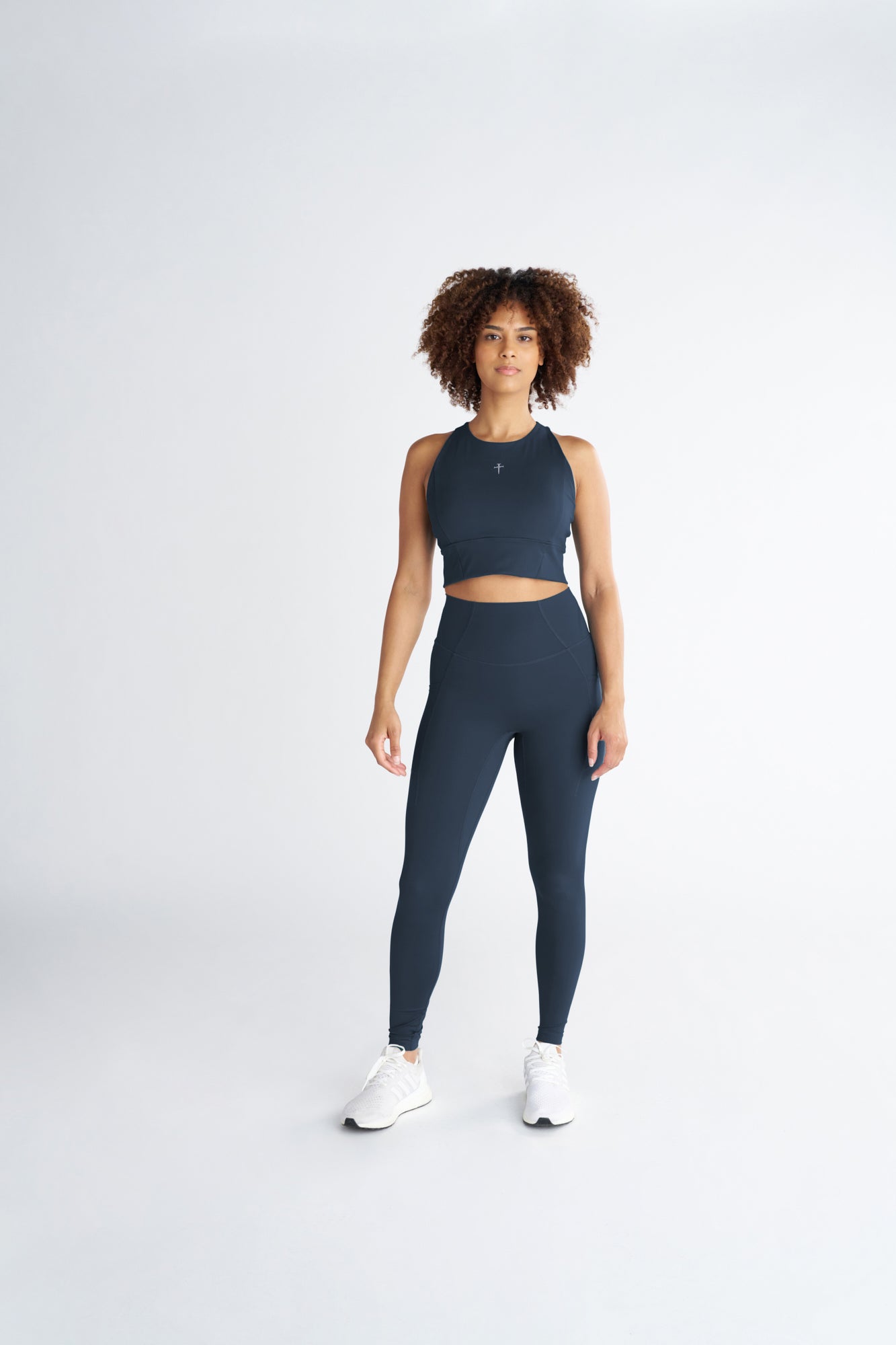 Front view of the Endura-Train Longline Bra in Midnight Navy worn with matching leggings and white sneakers.