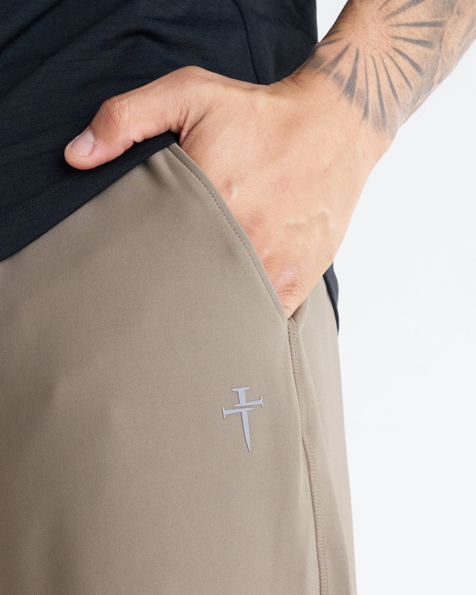 Close-up of Haven Performance Jogger in Sand showing side pocket and small Three Nails logo detail.