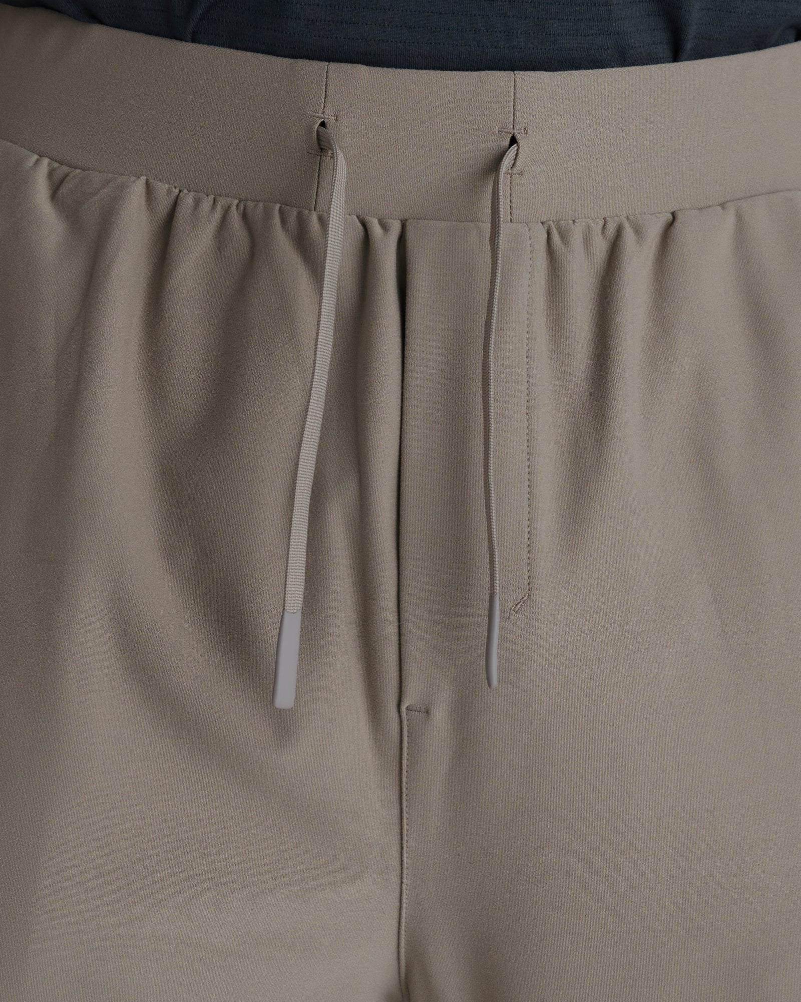 Close-up of Haven Performance Jogger in Sand showing elastic waistband, drawstring ties, and front seam detail.