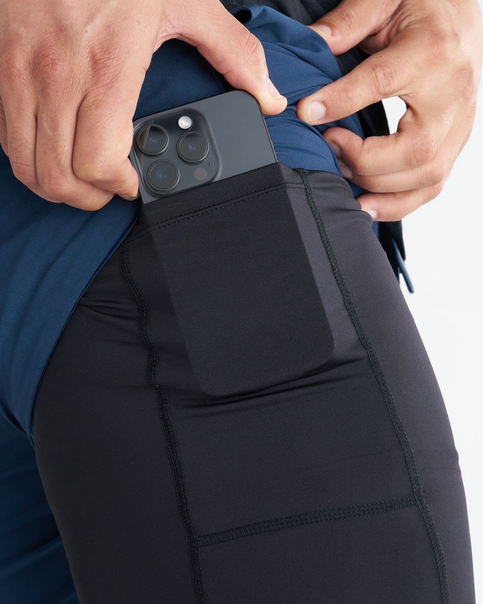 Close-up of Pulse Tech Liner Short in Midnight Navy showing a phone being inserted into the side thigh pocket.