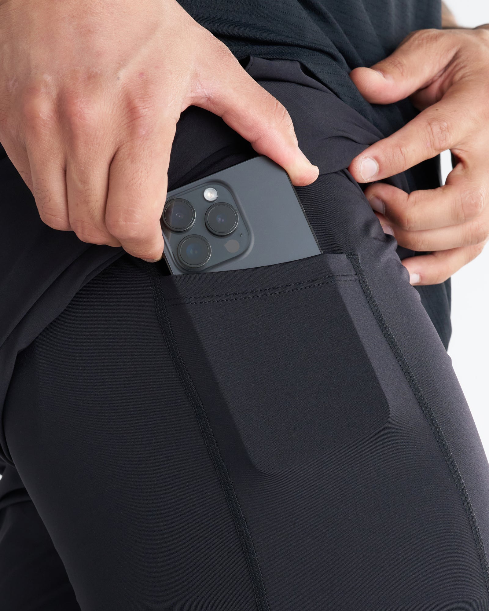 Close-up of the black Pulse Tech Liner Short side pocket with a phone being inserted.