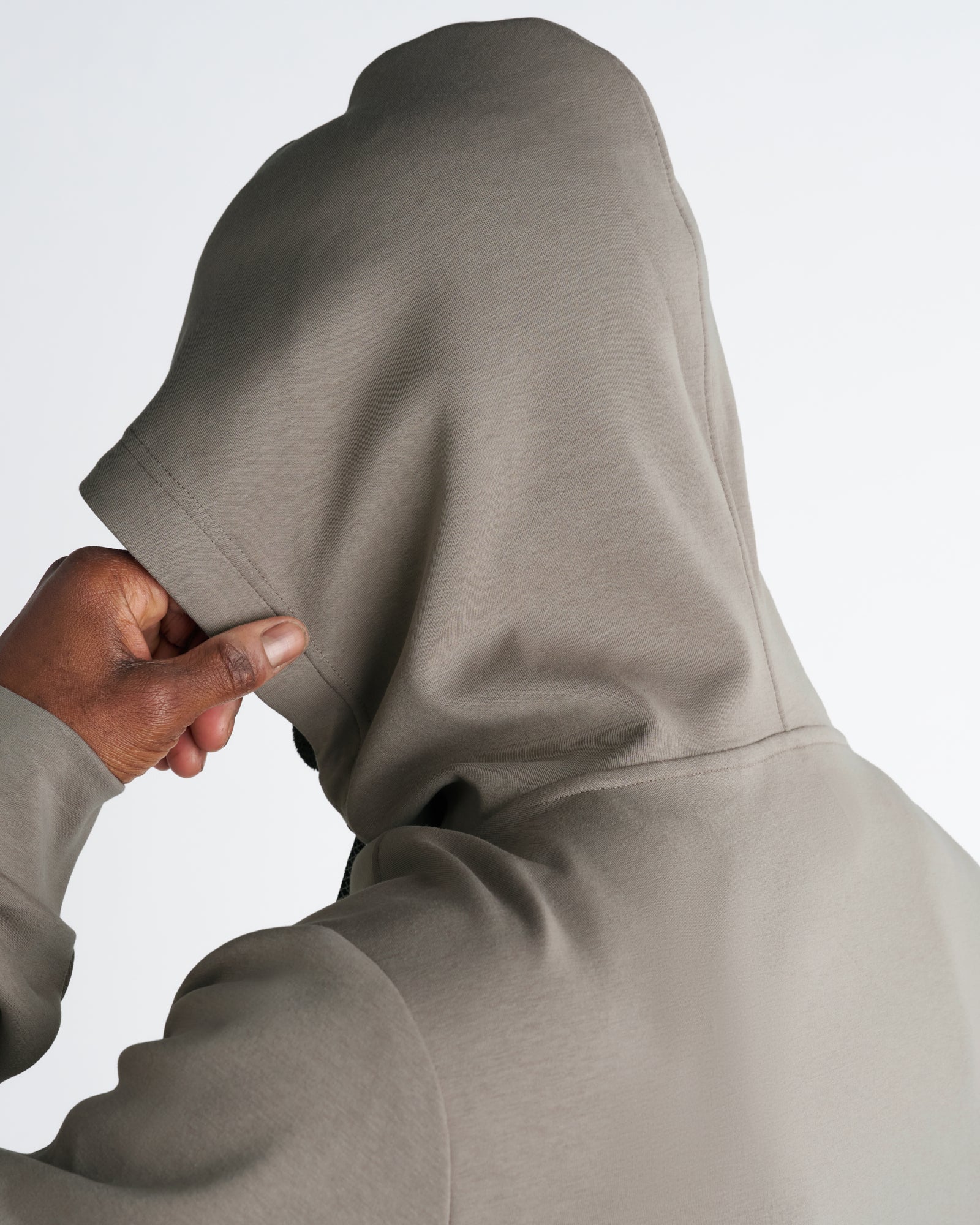 Close-up back view of the Pro-Tech Hoodie in Sand showing hood structure and sleeve cuff detail.