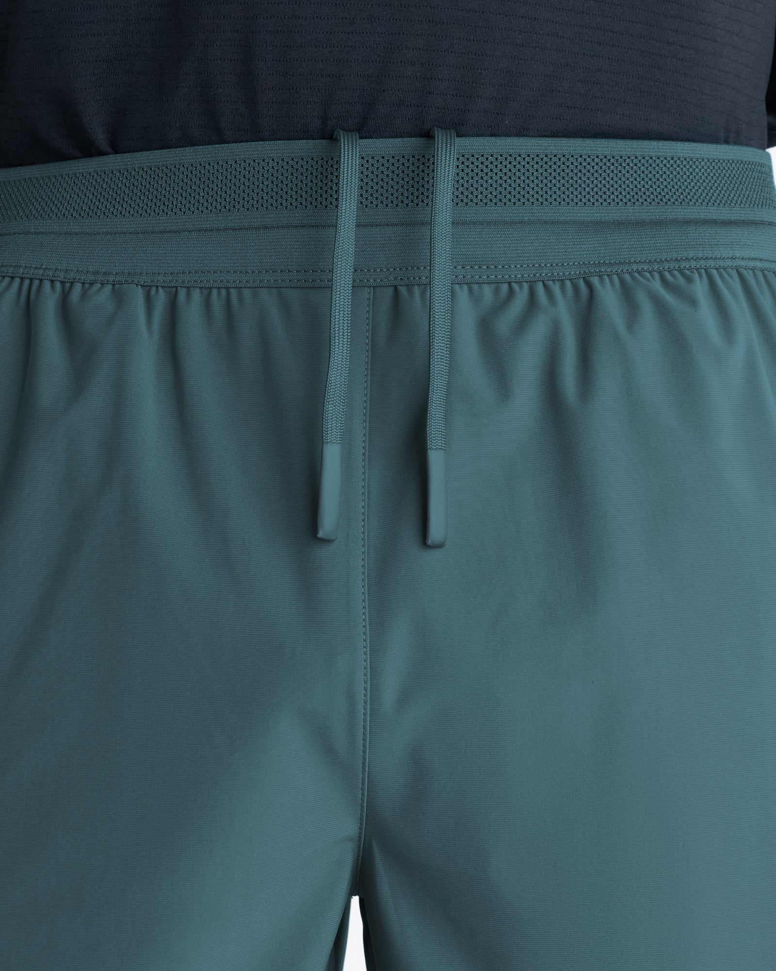 Close-up of the Vapor-Lite Hybrid Short in Teal showing the elasticated waistband, mesh panel, and drawstring detail.