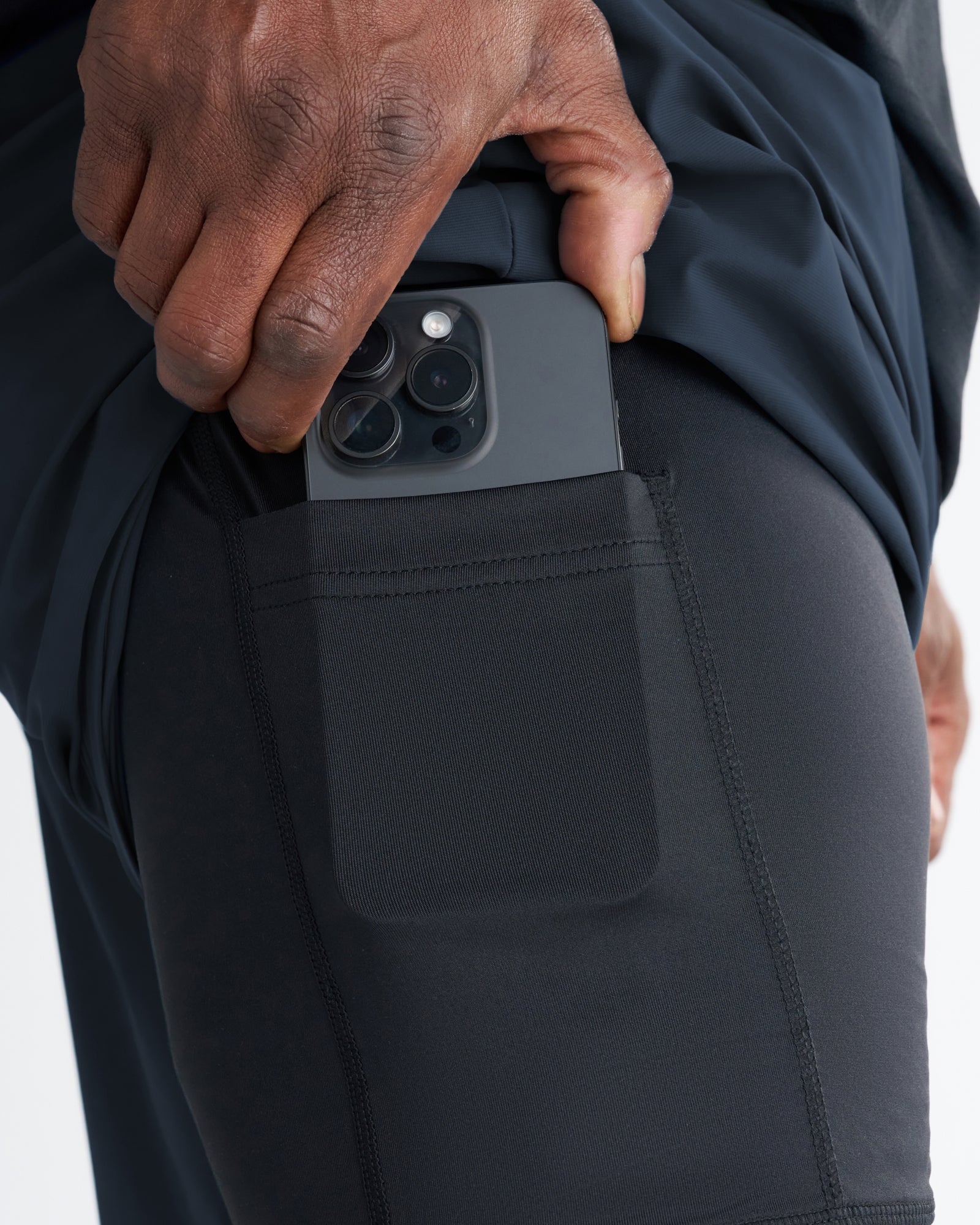 Close-up of Vapor-Lite Liner Short Cross in Midnight Navy showing side thigh pocket with iPhone being inserted.