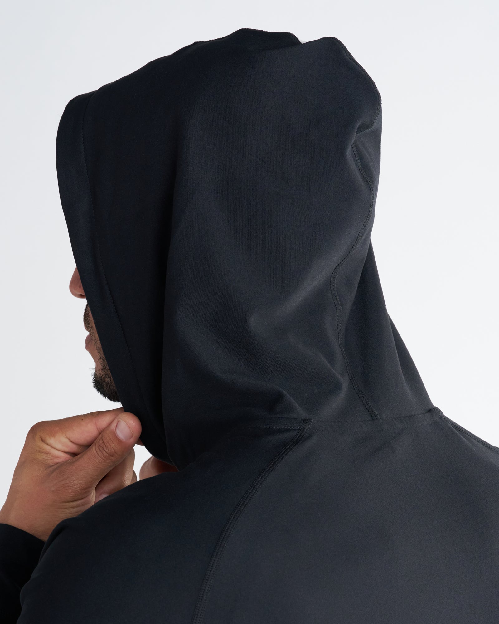 Close-up side angle of the Haven Performance Hoodie in black showing the structured hood design on a male model.