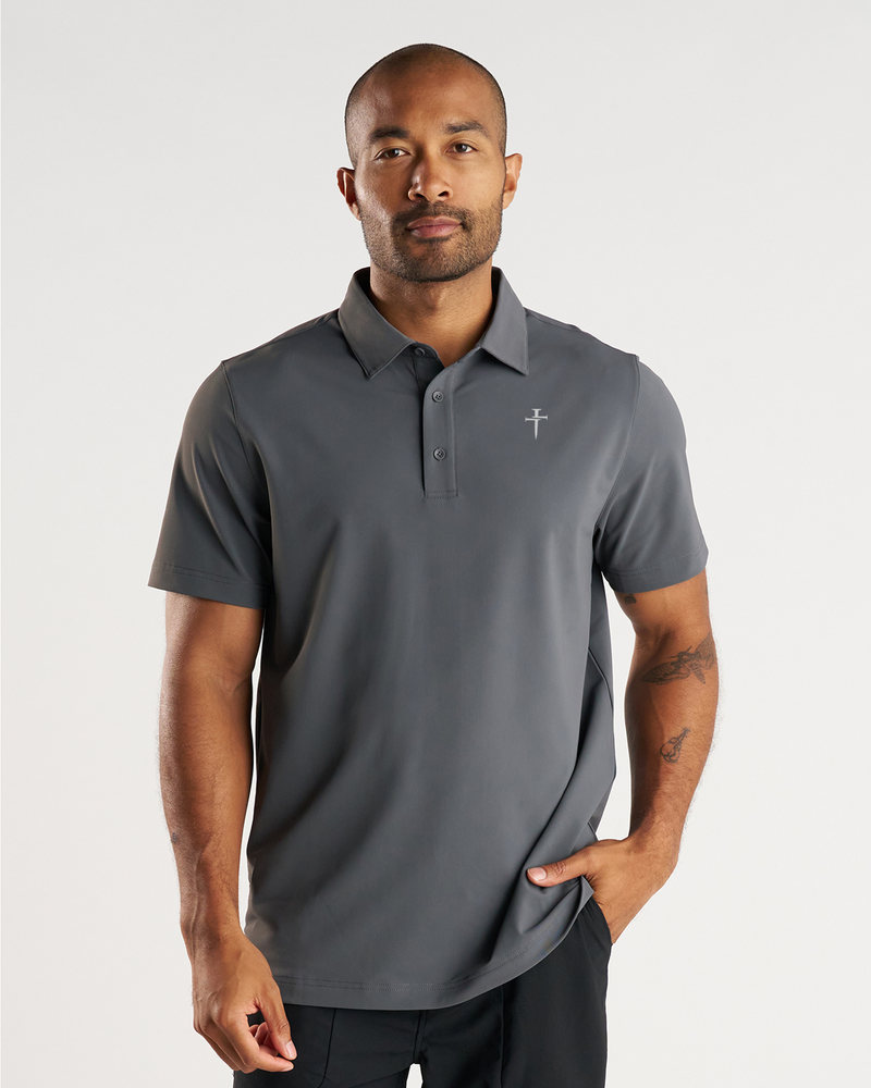 Man wearing Vented Tech Polo in charcoal gray, front view, featuring a cross logo on chest and three-button placket.