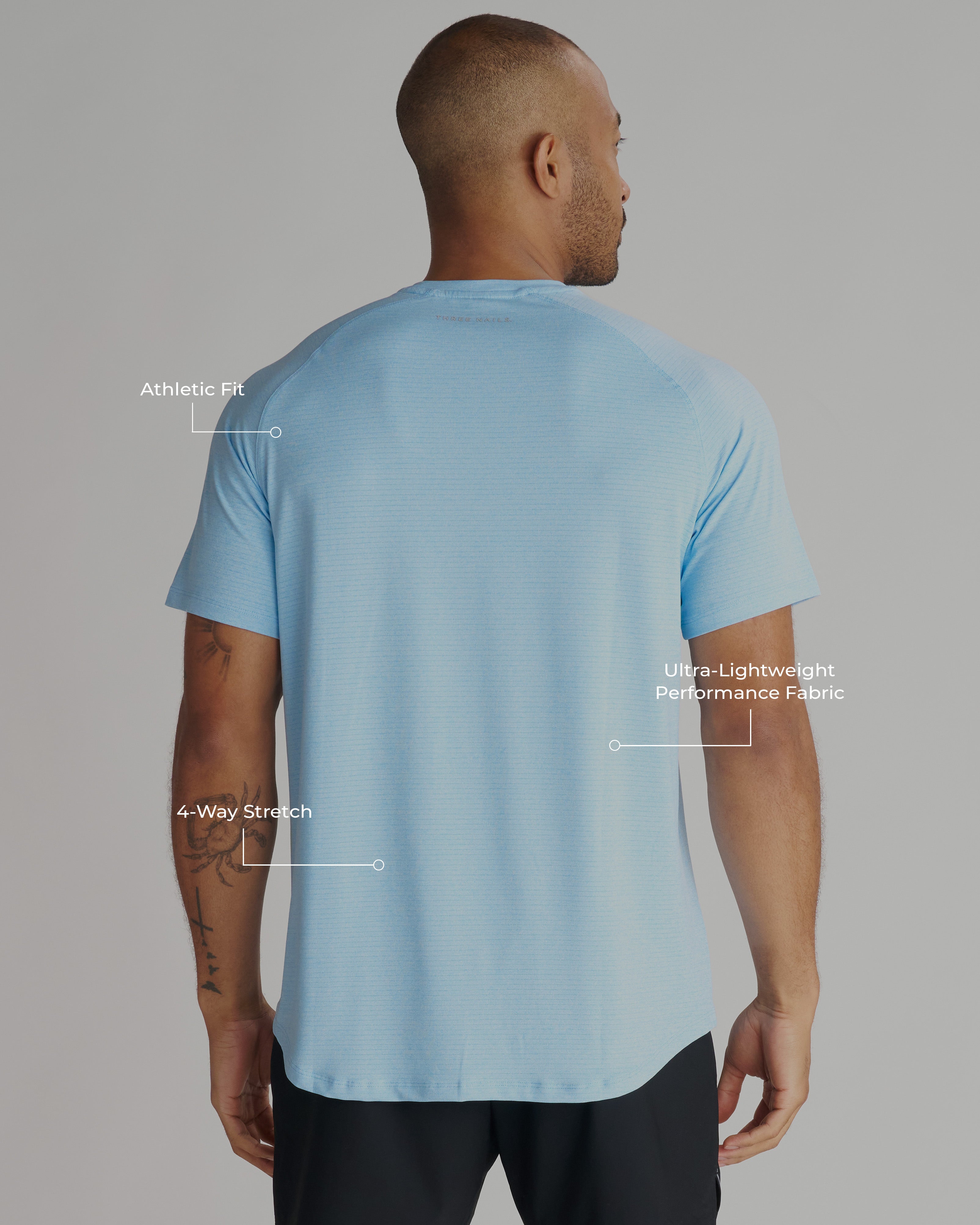 Back view of model wearing the Aion-Lite Tee Cross in Sky Blue Marl with feature callouts visible.