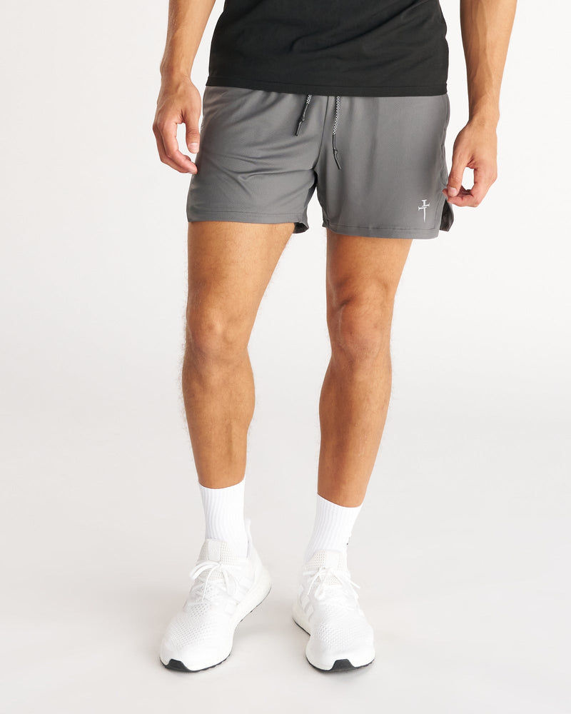 Man wearing Pro-Tech 2.0 Liner 5" Short Bundle Pack in gray, front view, paired with white sneakers.