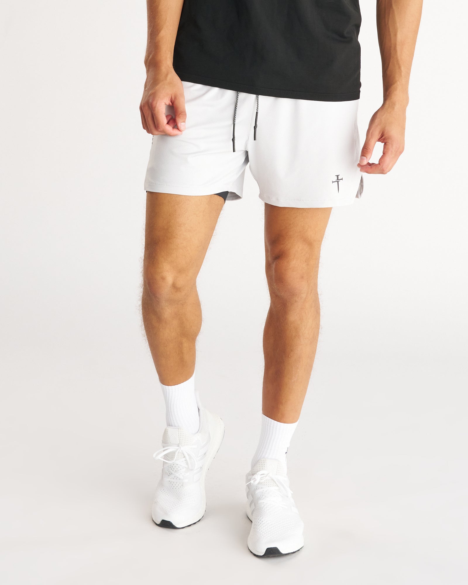 Man wearing white Pro-Tech 2.0 Liner 5" Shorts, front view, paired with black tee and white sneakers.