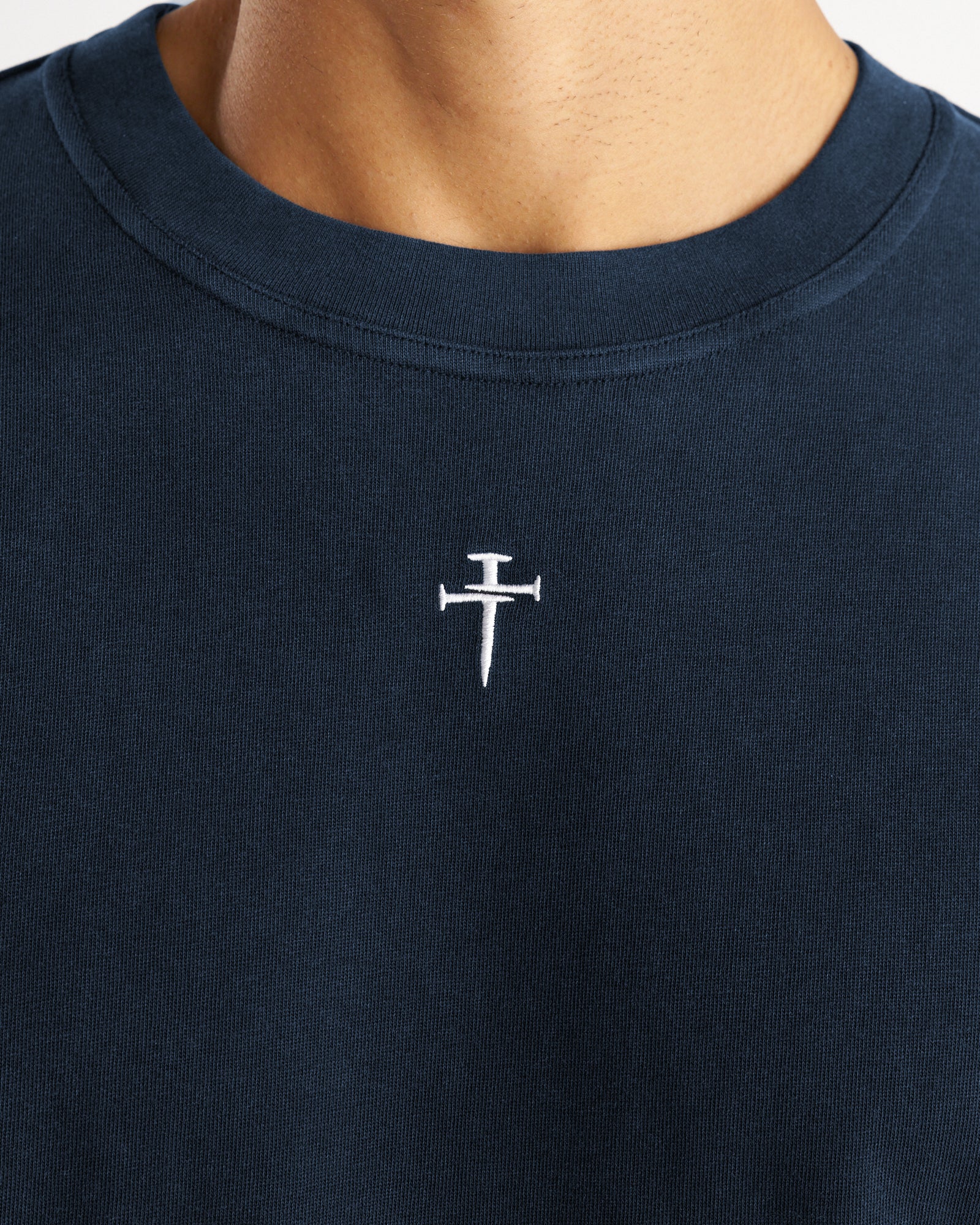 Close-up detail of Midnight Navy Heavyweight Cotton Oversized Tee FHG showing white nail cross embroidery at chest.