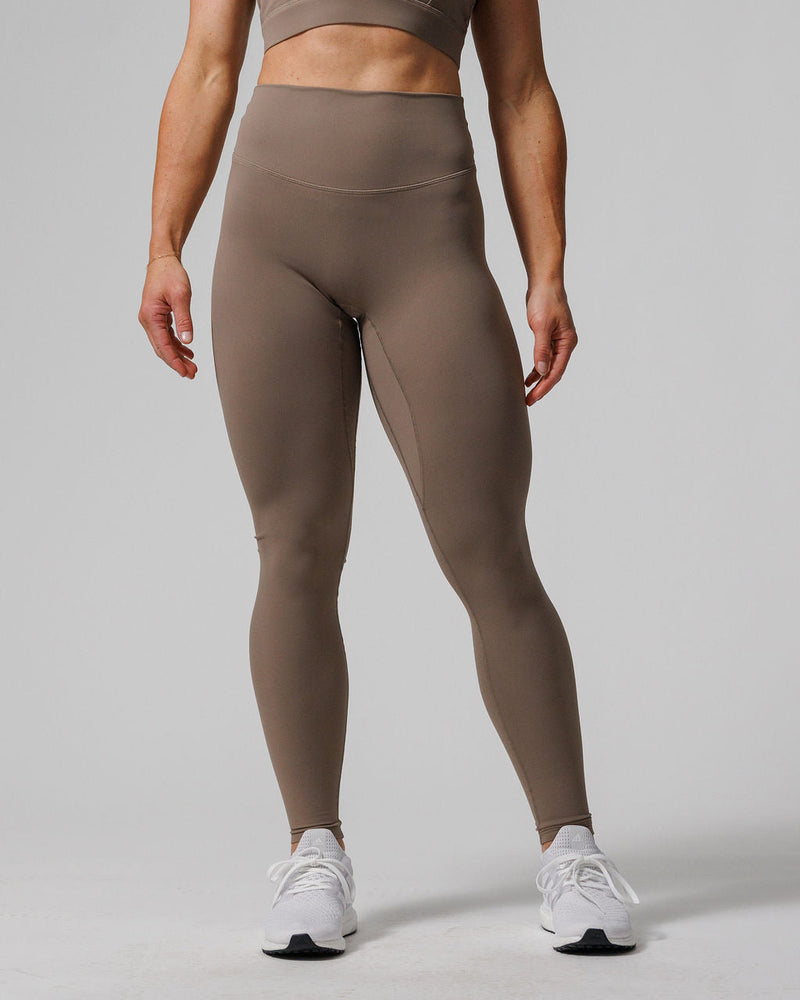 Nova Legging 27" in taupe worn by a model, front view, full-length high-waist fit with white sneakers.