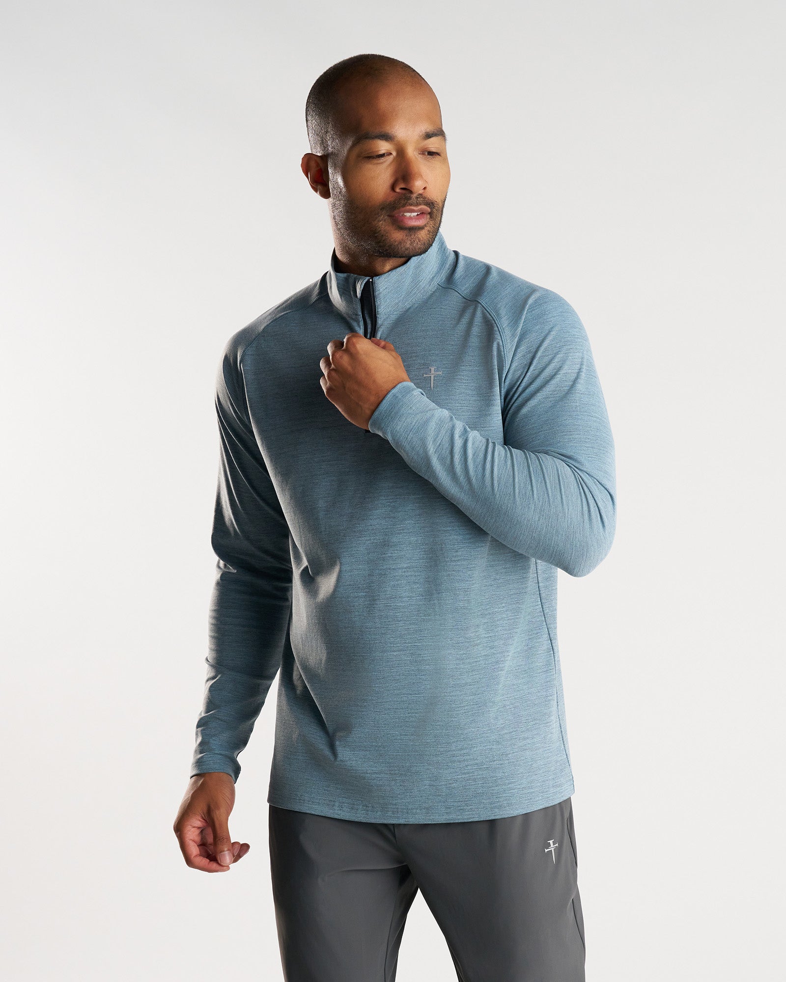Man wearing Core Quarter Zip in heathered blue, front view, hand raised to zip collar.