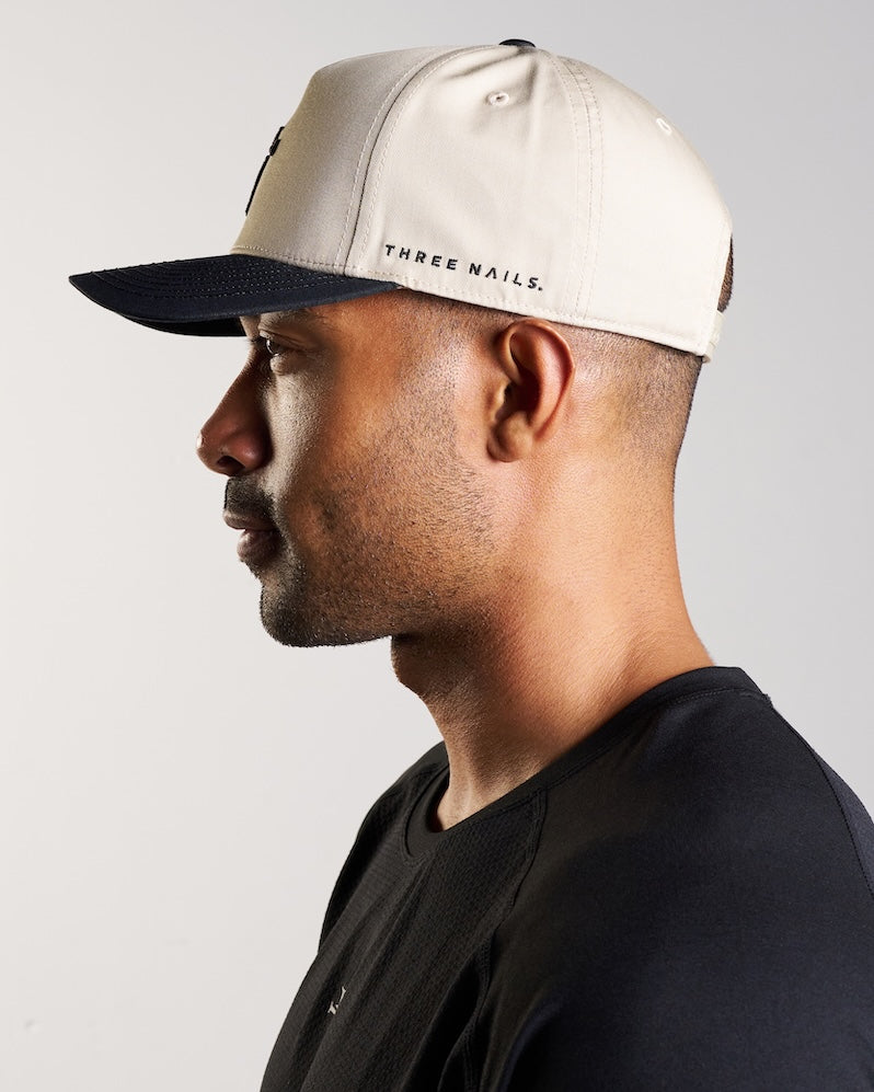 Man wearing the Signature Two-Tone Hat in cream and black, side profile view showing brim and logo detail.
