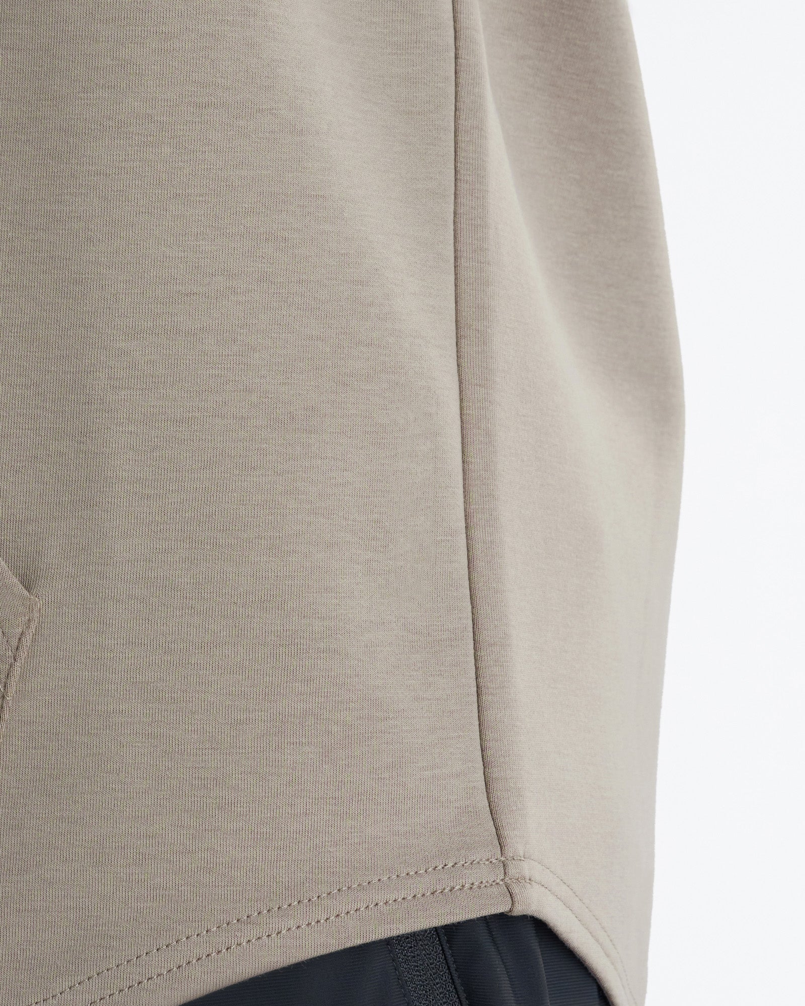 Close-up detail of the Pro-Tech Hoodie in Sand showing side seam stitching and hem construction.