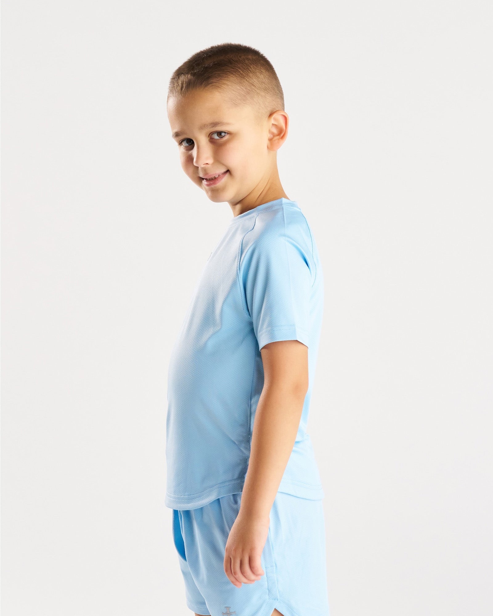 Youth Pro-Tech Tee Cross in Sky Blue shown at a side angle on a young boy model.