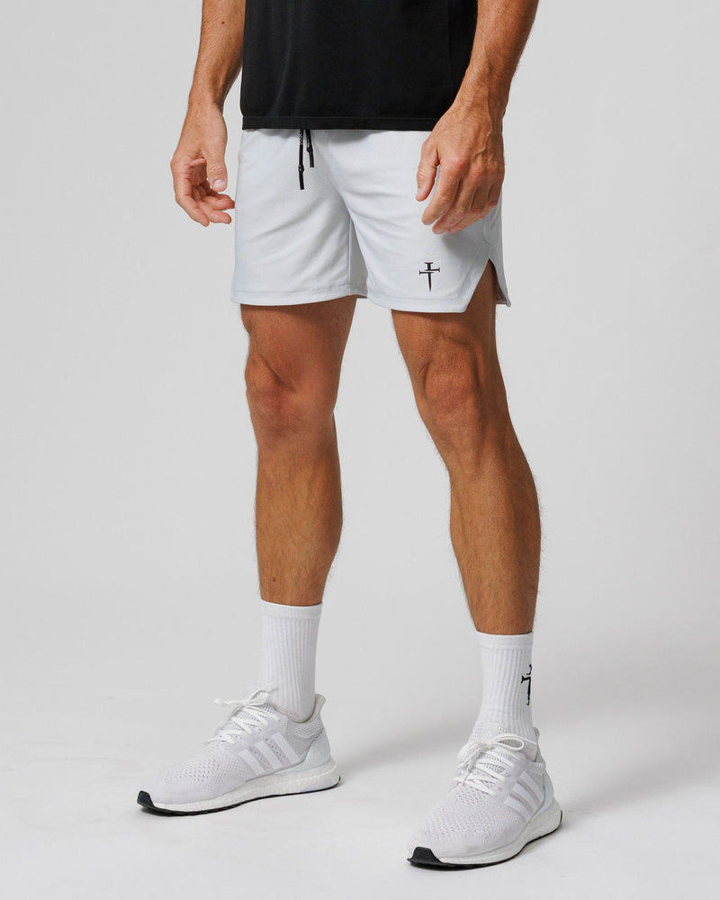 Man wearing Pro-Tech 2.0 Linerless Shorts in white, side angle view, paired with white Adidas sneakers and matching socks.