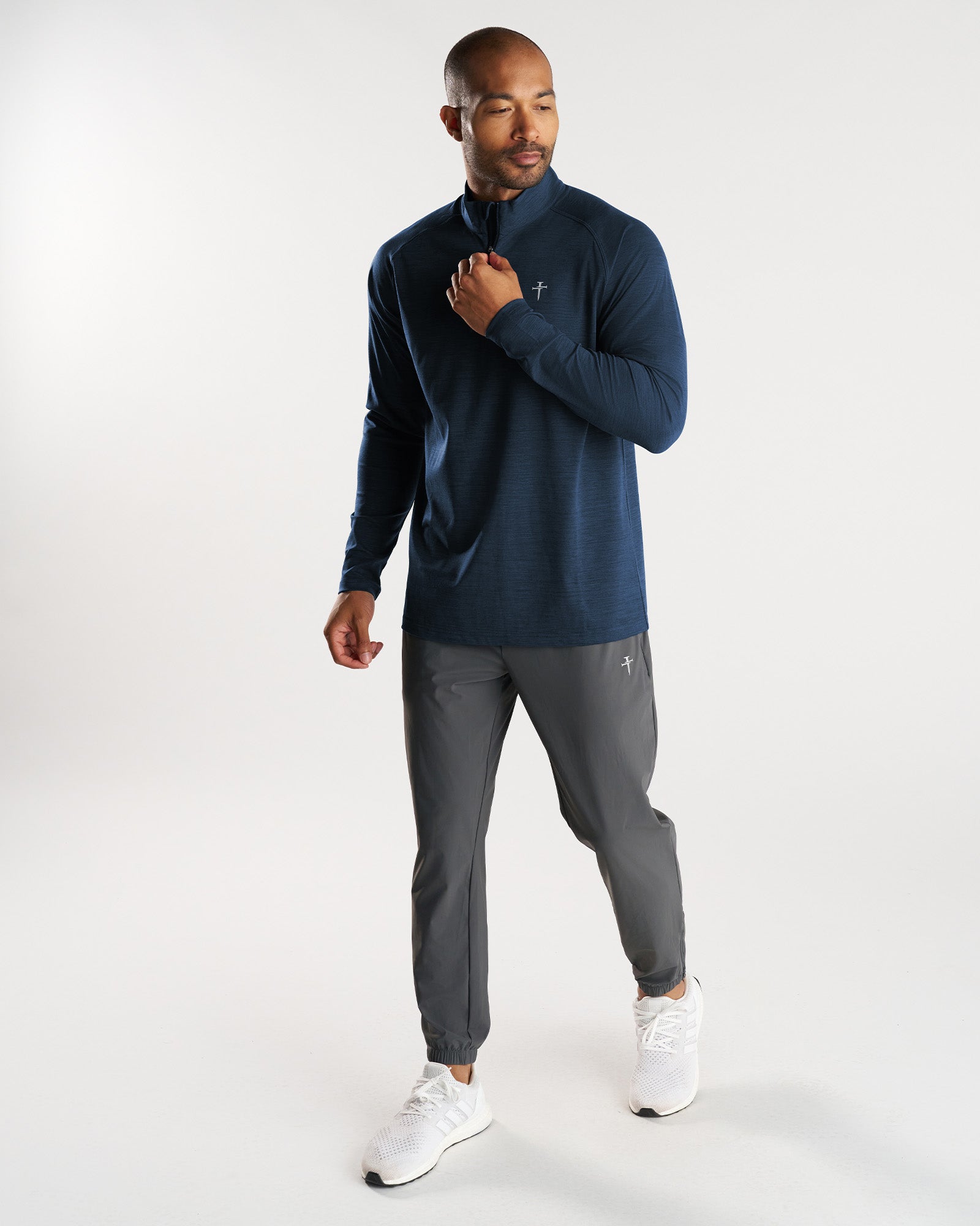 Man wearing Core Quarter Zip in Midnight Navy, front view, paired with gray joggers and white sneakers.