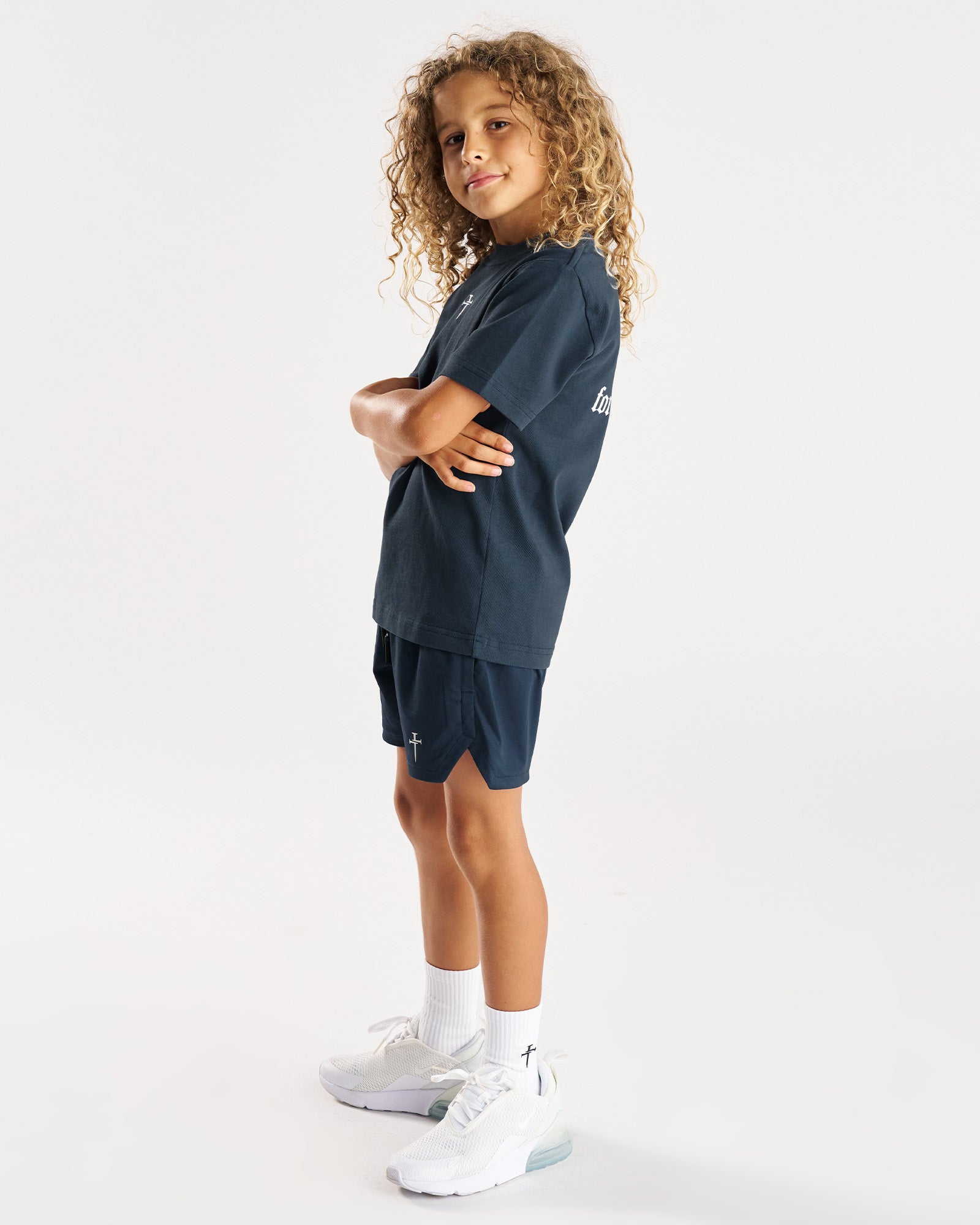 Youth Heavyweight Cotton Oversized Tee FHG in Midnight Navy on a child model, side angle with arms crossed.