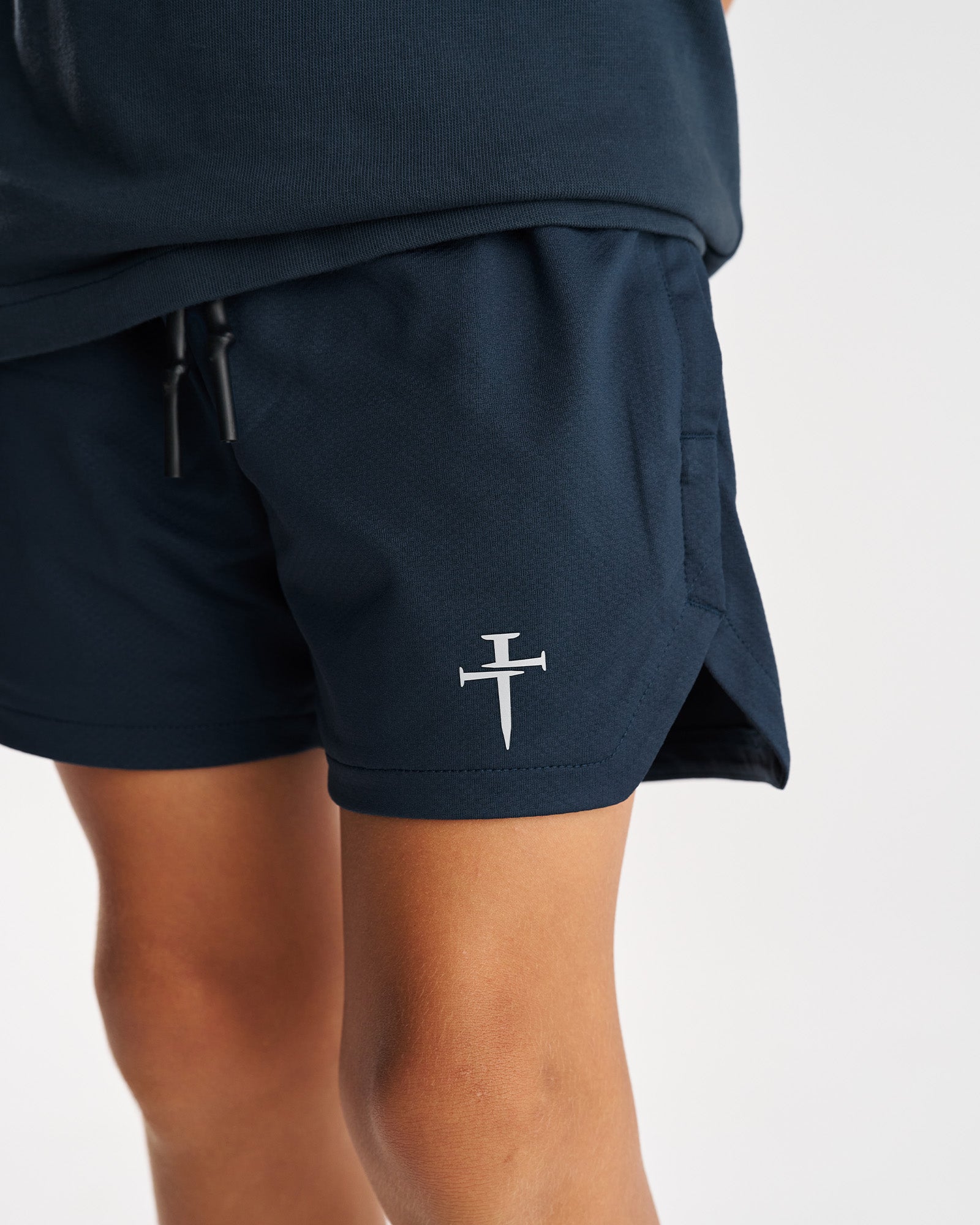 Close-up of Youth Pro-Tech 2.0 Linerless Short in Midnight Navy showing the Three Nails logo and side pocket detail.