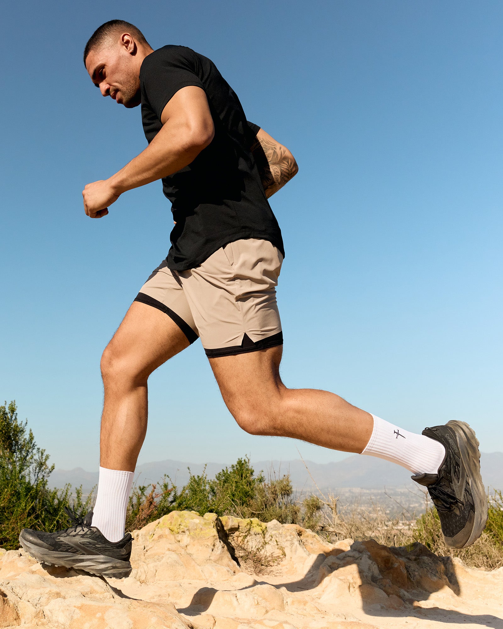 Man running outdoors in side view wearing the Pulse Tech Liner Short in Sand with black compression liner visible.