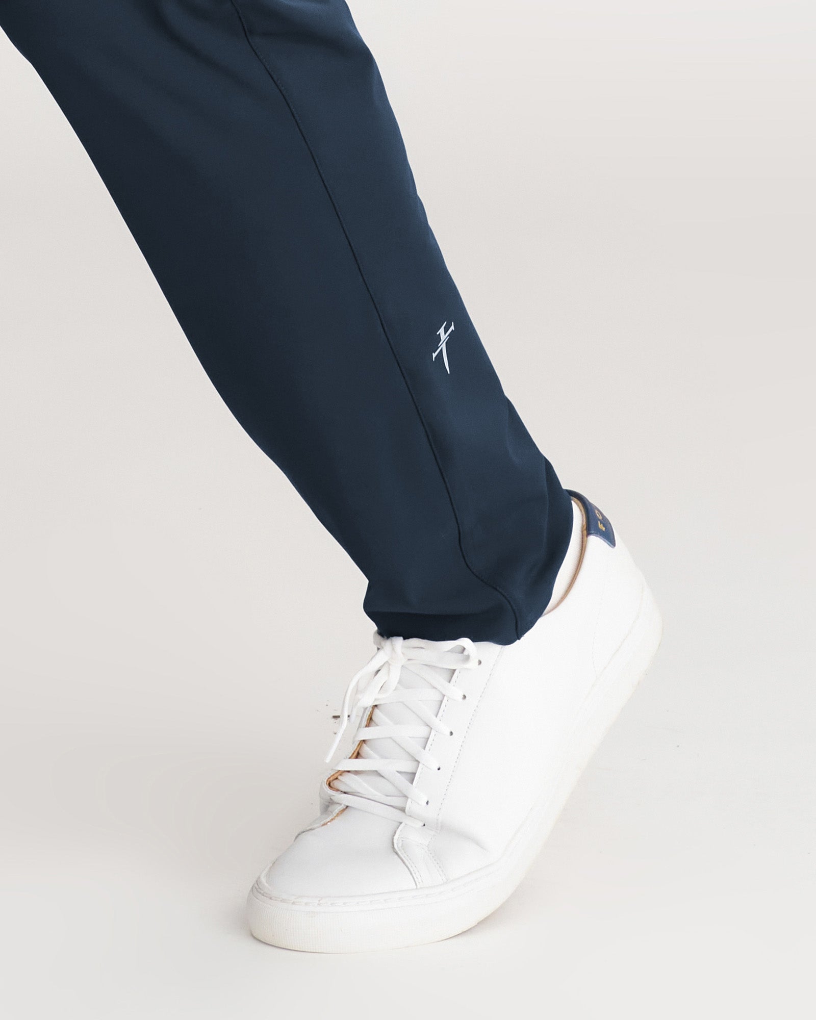 Close-up of Links Golf Pant in Midnight Navy showing lower leg logo detail and white sneaker styling.